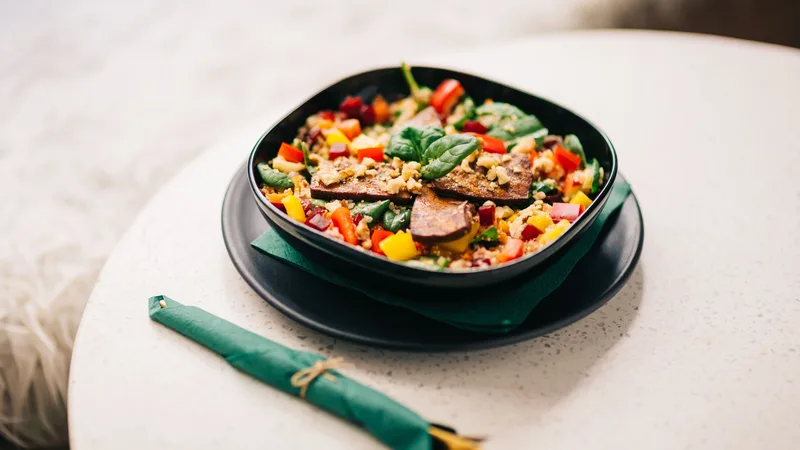 Siyah kase içinde renkli sebze, tahıl ve protein kaynaklarından oluşan dengeli bir öğün, üstten çekim